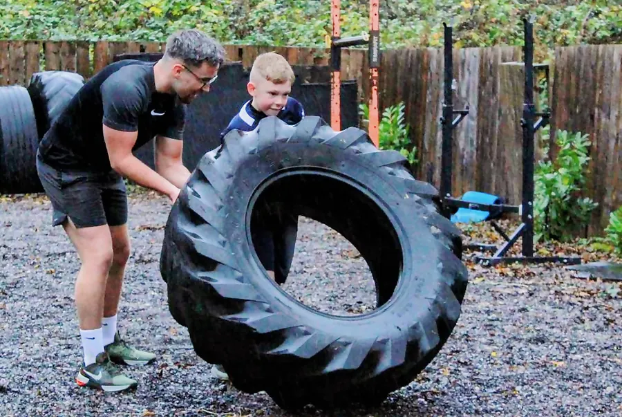Cat coaching a young athlete through a tyre flip at ID FIT